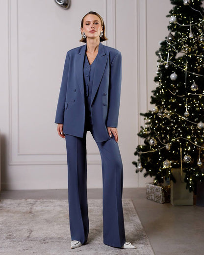 Woman in a blue suit standing in front of a decorated Christmas tree.