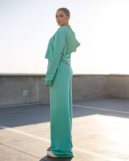 Person wearing a teal outfit on a rooftop with a clear sky.