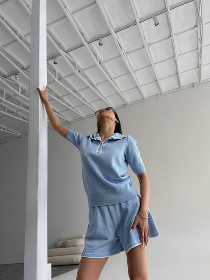 Person wearing a blue outfit standing in a minimalistic room with white walls and ceiling.