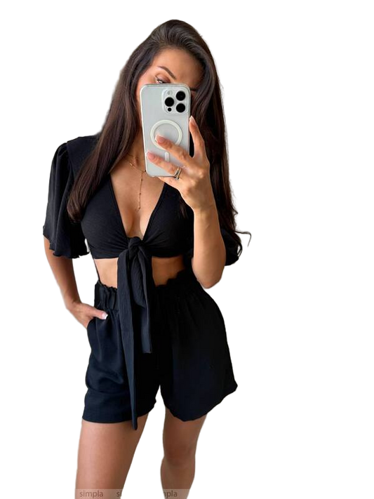 Woman taking a mirror selfie wearing a black outfit with a white background