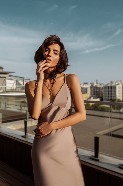 Woman in a beige dress standing on a rooftop with cityscape in the background