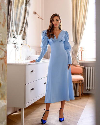 Woman in a light blue dress standing in a bathroom.