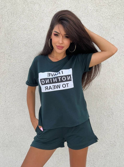 Woman wearing a dark green t-shirt with text and shorts against a light gray background