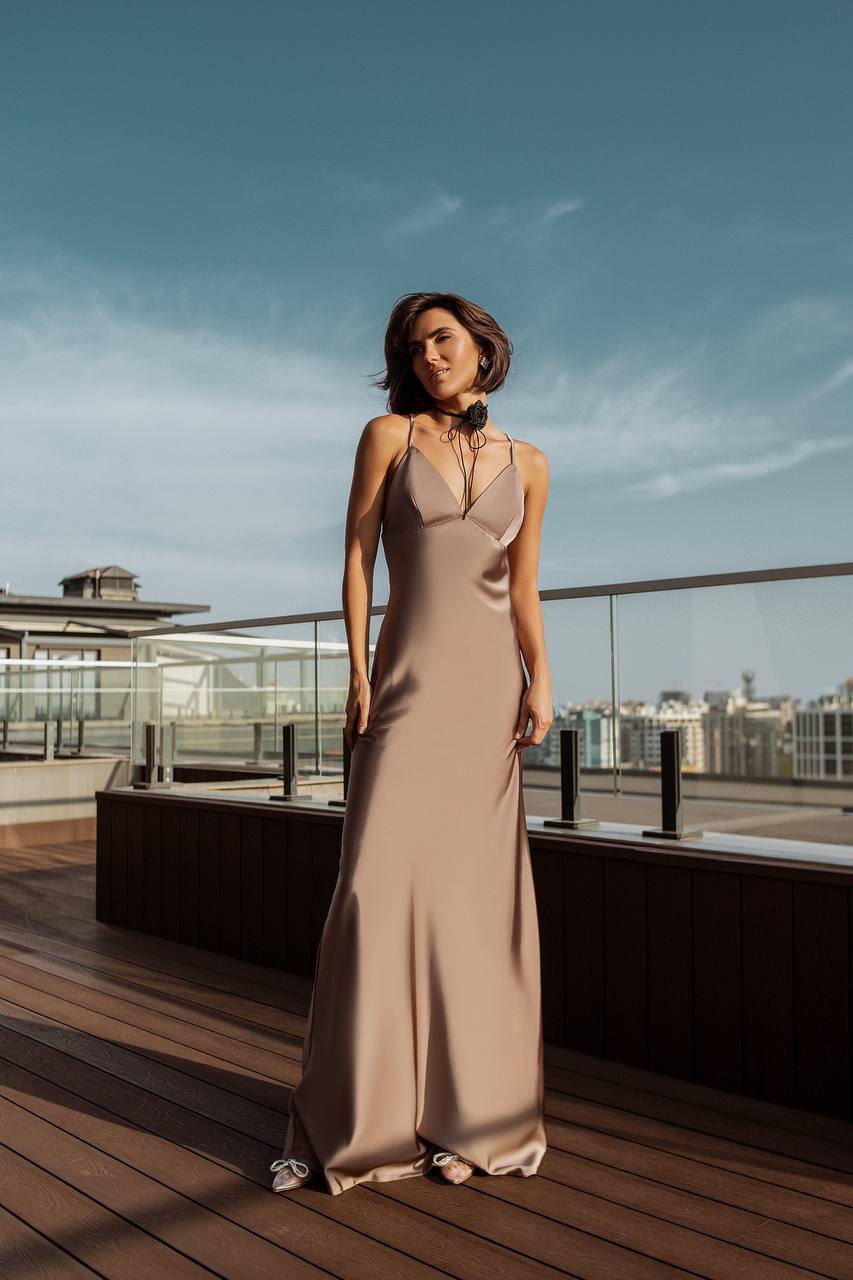 Woman in a beige dress standing on a rooftop with a cityscape in the background