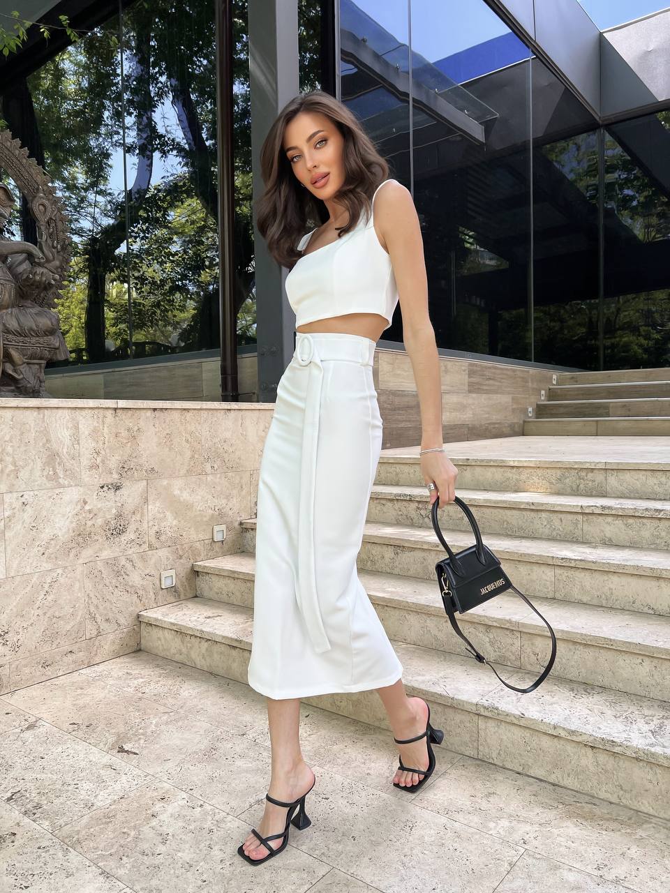 Woman in white outfit standing on steps outside a modern building