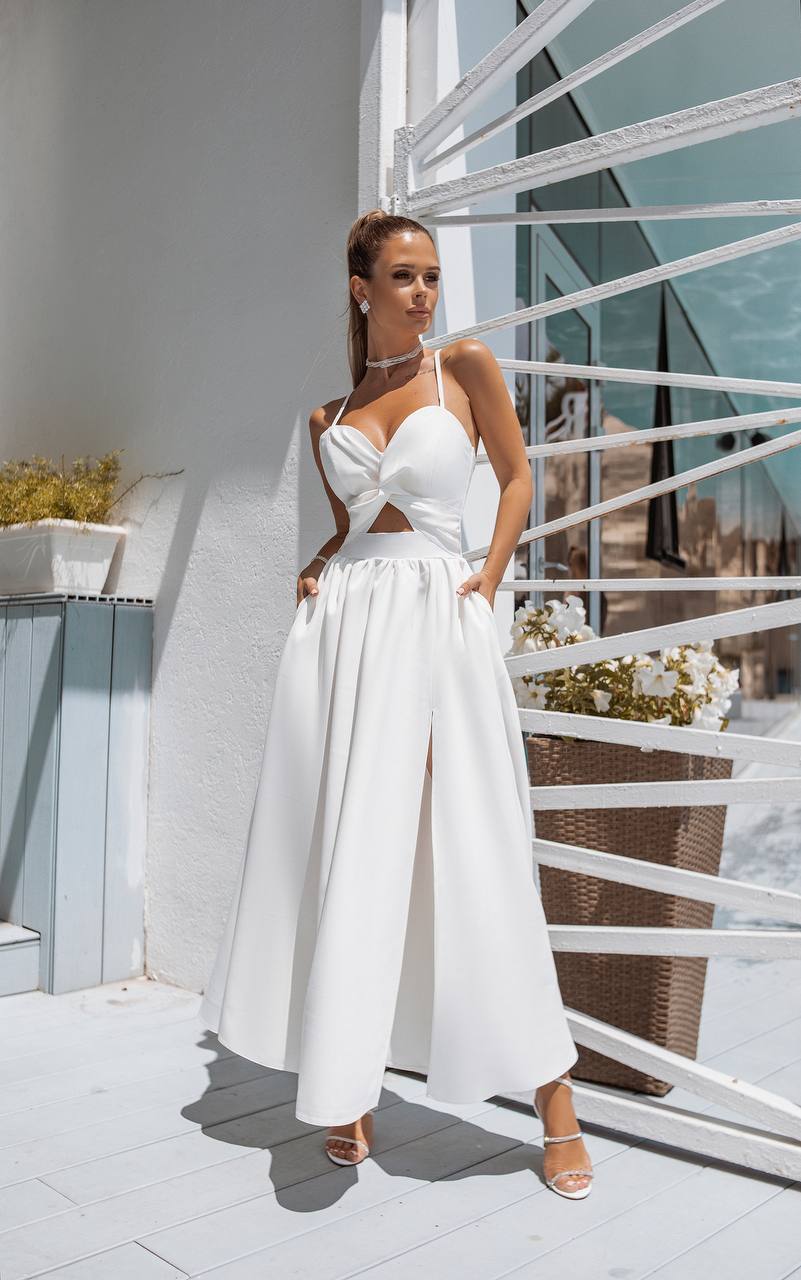 Woman in a white dress standing on a rooftop with modern architectural elements.