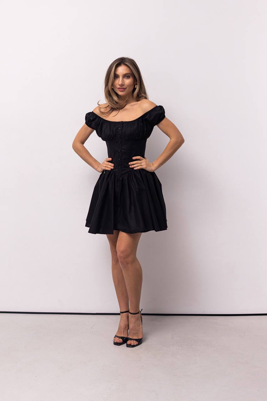 Woman wearing a black off-shoulder dress against a white background