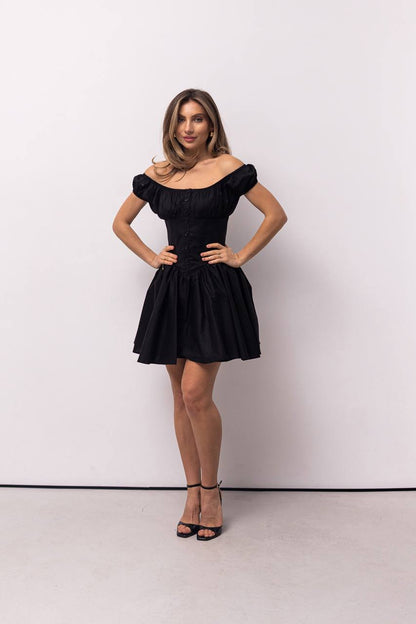 Woman wearing a black off-shoulder dress against a white background