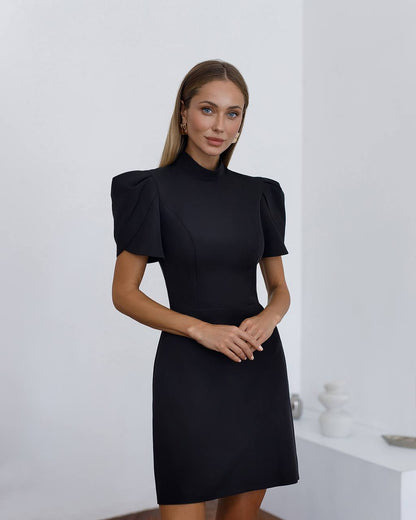 Woman wearing a black dress with puffed sleeves against a white background