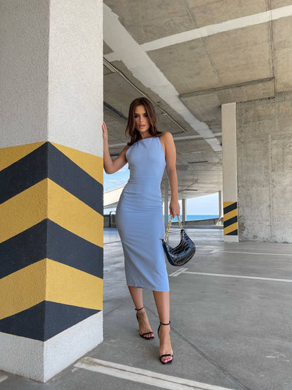 Woman in a light blue dress standing in an underpass with a striped wall.