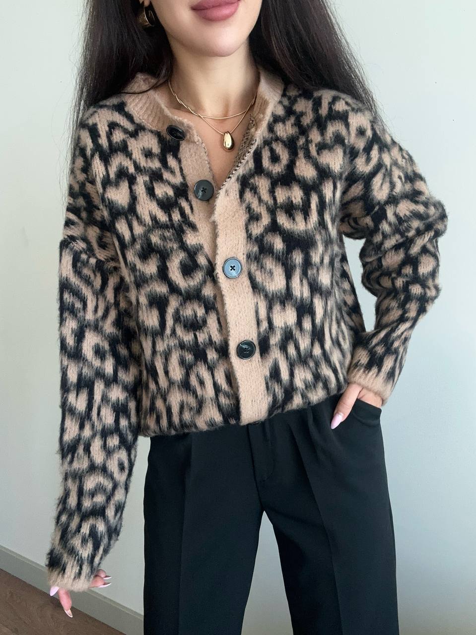 Person wearing a leopard print cardigan with a plain background