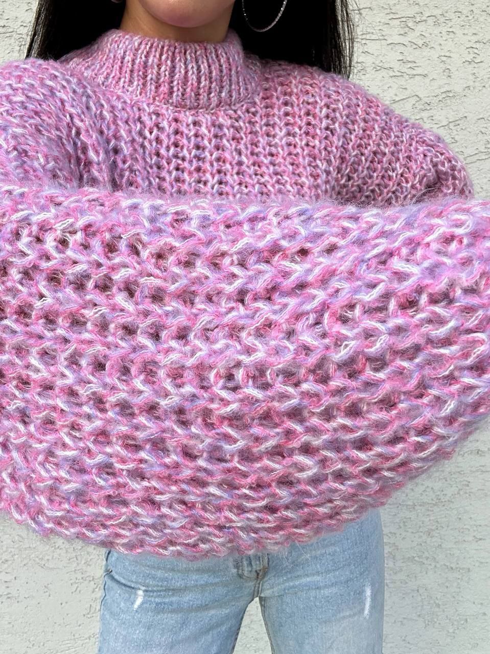 Close-up of a pink knitted sweater with a textured pattern.