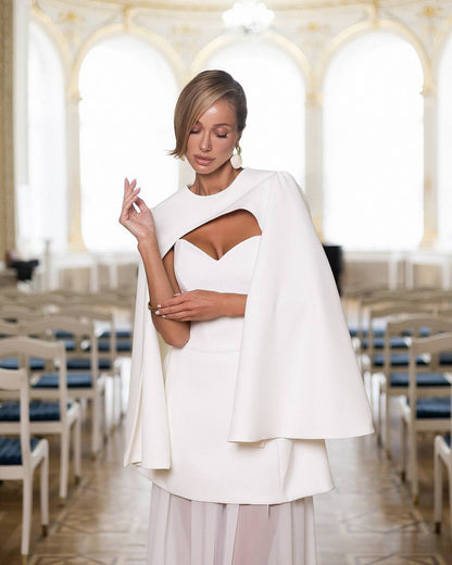 Woman in a white dress with a cape in an elegant indoor setting