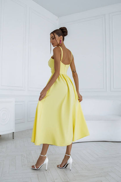 Woman in a yellow dress standing in a minimalistic room with white walls and floor.
