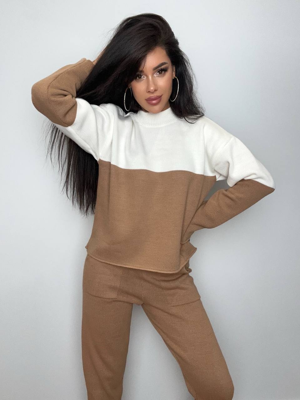 Woman wearing a brown and white color-blocked outfit against a plain background
