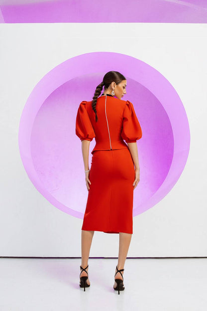 Woman in a red dress standing against a white background with a large pink circle.
