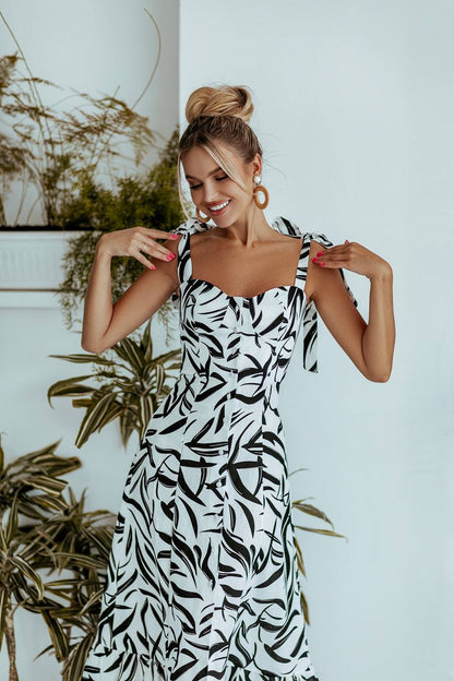 Woman wearing a black and white patterned dress with plants in the background
