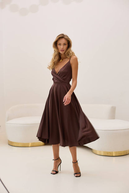 Woman wearing a brown dress standing in a modern interior setting