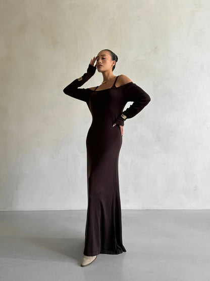 Woman wearing a dark brown off-shoulder dress against a plain background