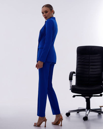 Woman in a blue suit standing next to a black office chair on a white background
