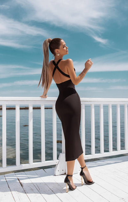 Woman in a black dress standing on a wooden deck with a blue sky and water background