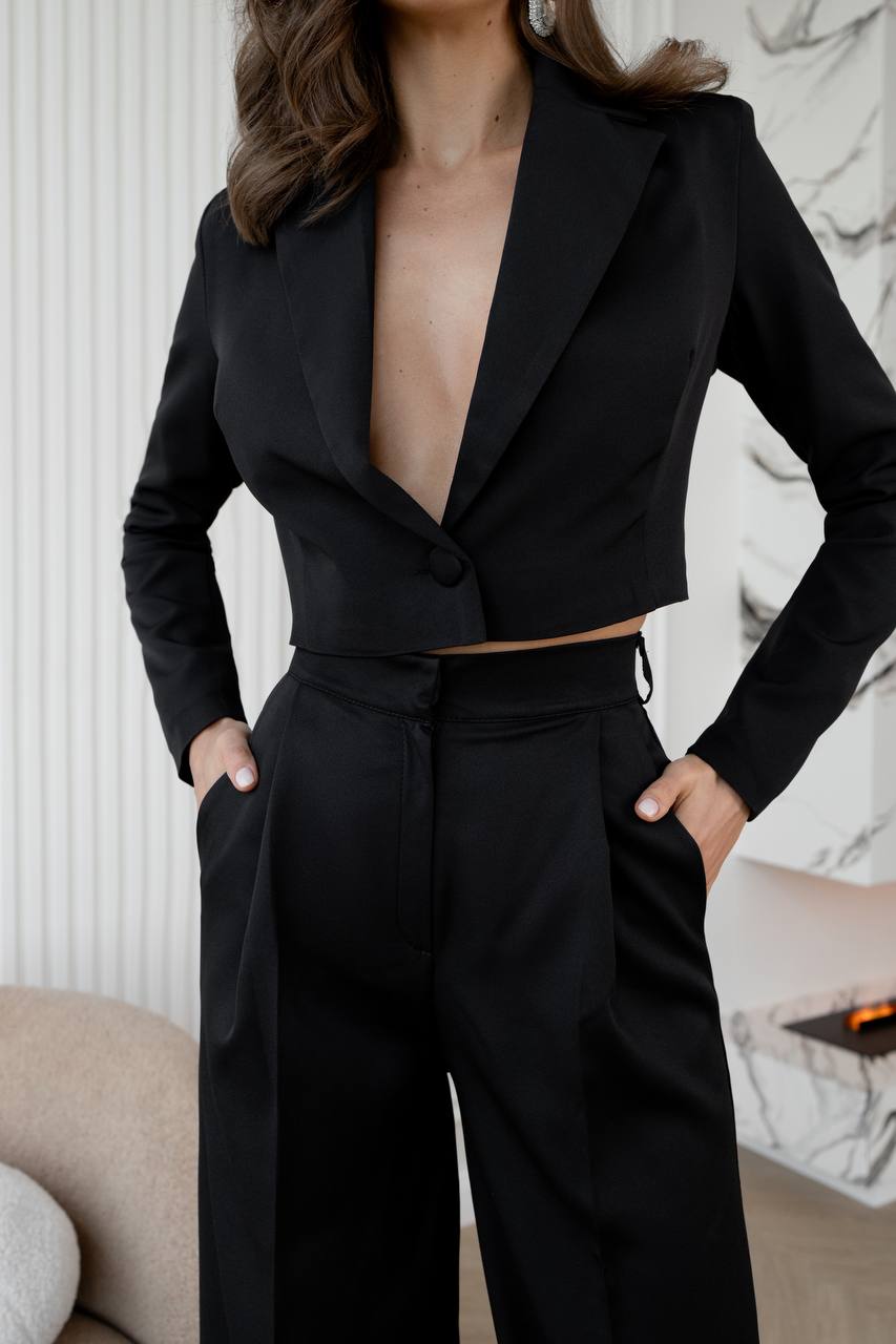 Person wearing a black suit with a deep neckline in an indoor setting.