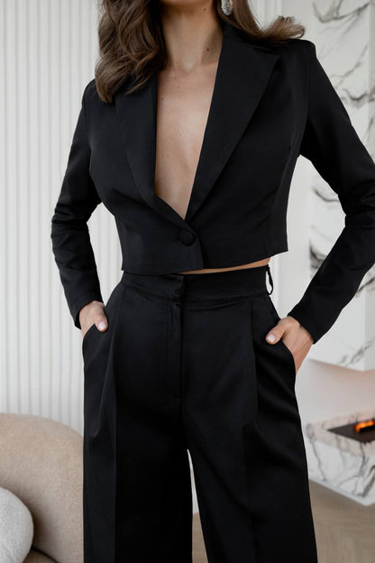 Person wearing a black suit with a deep neckline in an indoor setting.
