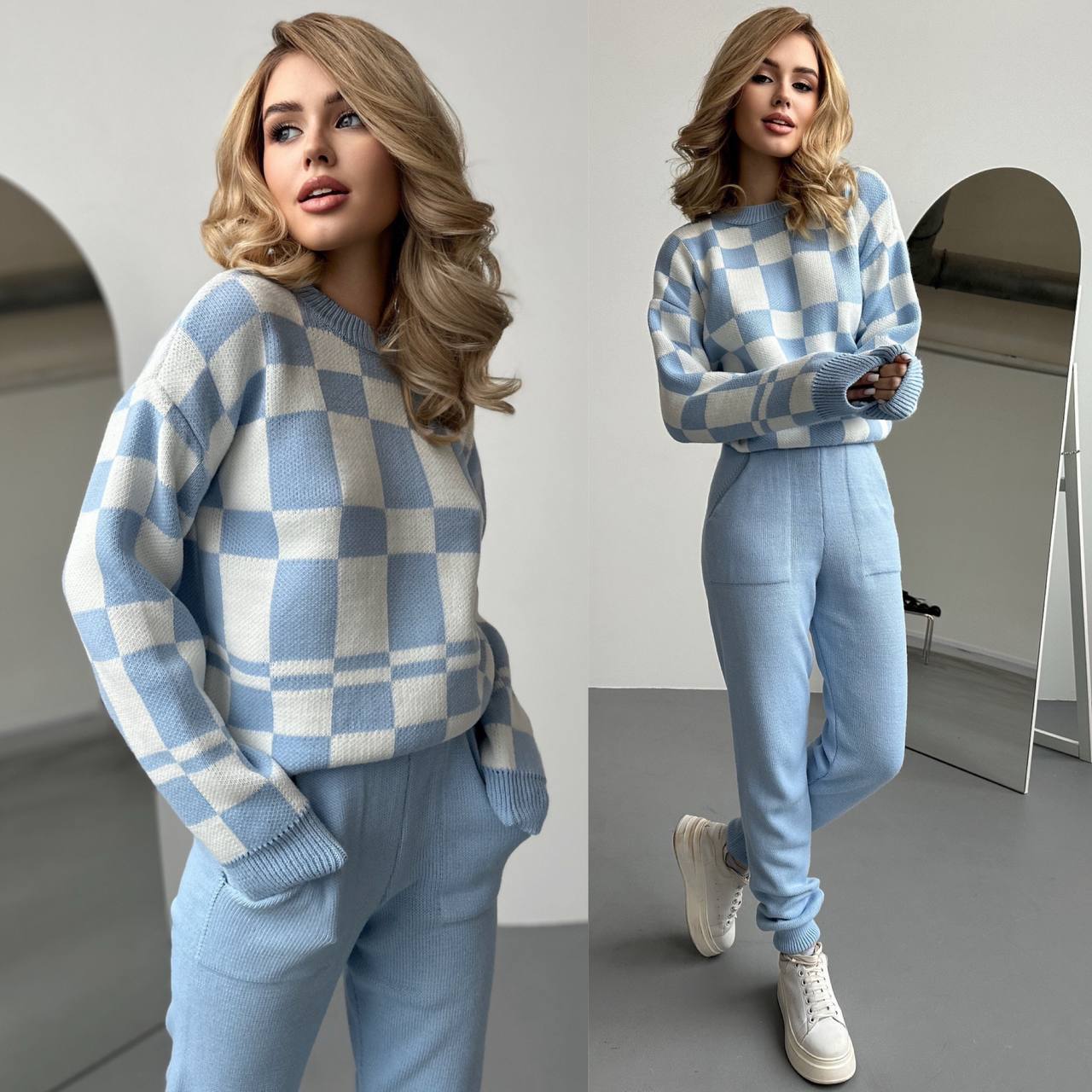 Woman wearing a blue and white checkered sweater and pants set in a minimalistic room.