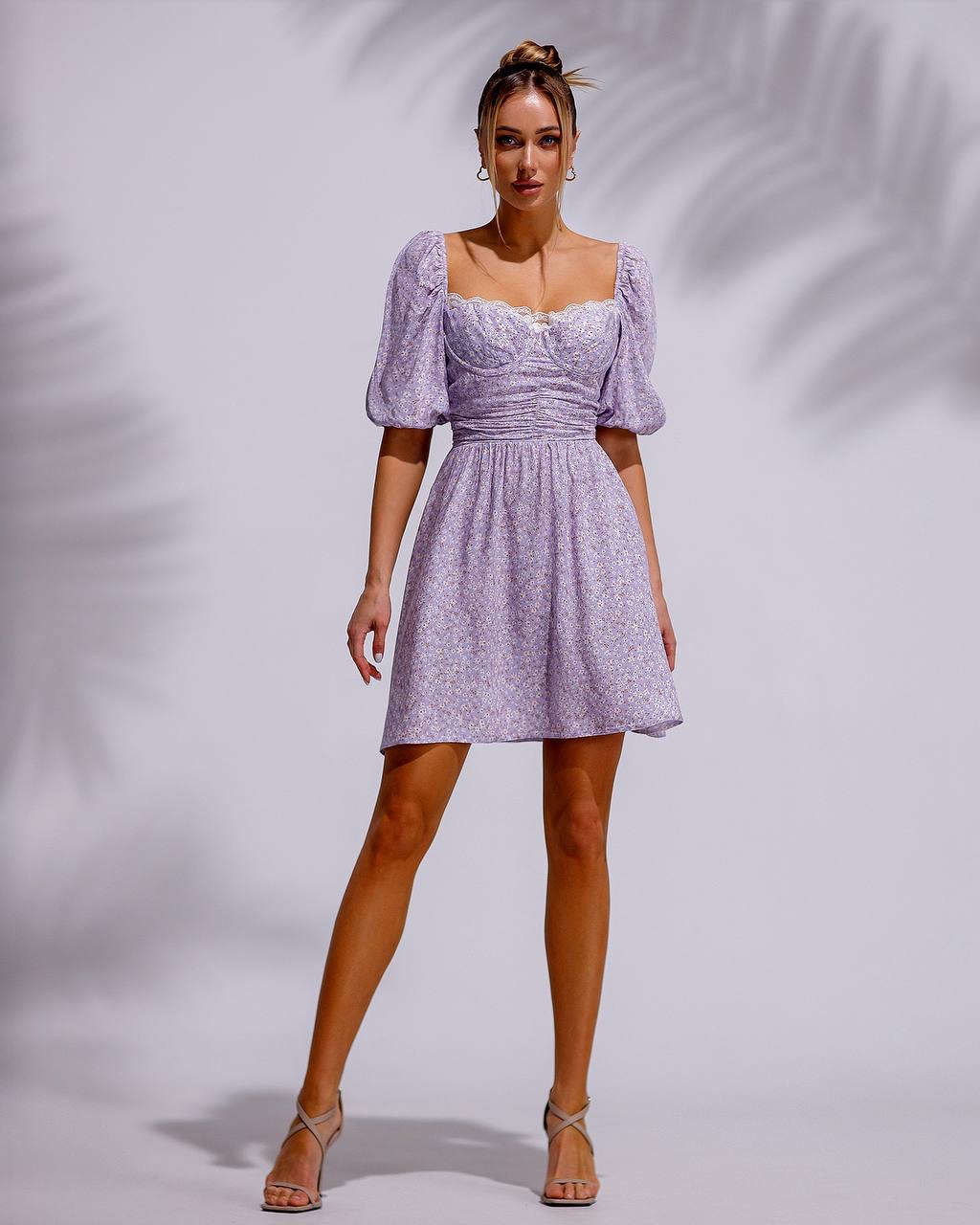 Woman wearing a light purple dress with puff sleeves against a plain background