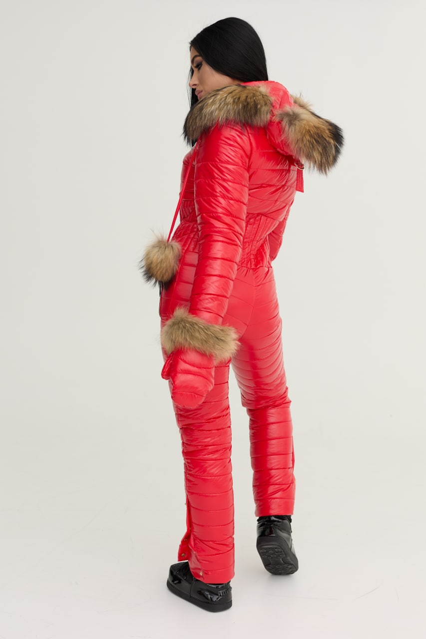 Person wearing a red puffer jumpsuit with fur trim on a white background