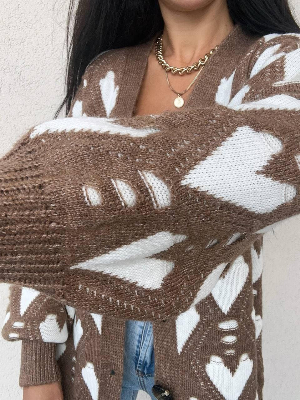 Close-up of a person wearing a brown and white patterned sweater with a neutral background