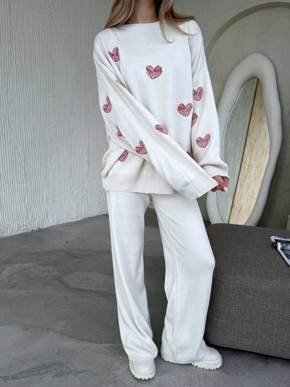 Person wearing a white outfit with heart patterns in a minimal indoor setting
