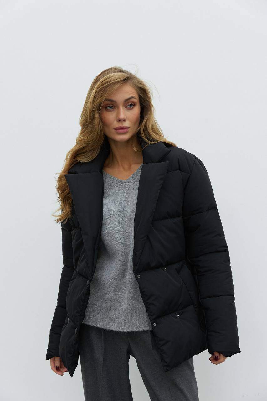 Woman wearing a black puffer jacket over a gray sweater on a white background