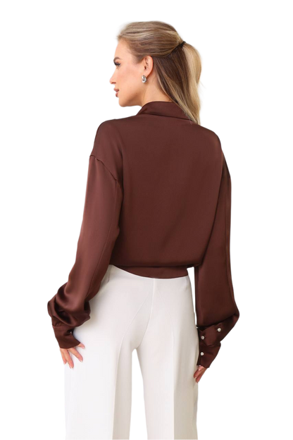 Woman wearing a brown blouse with long sleeves and a high collar on a white background