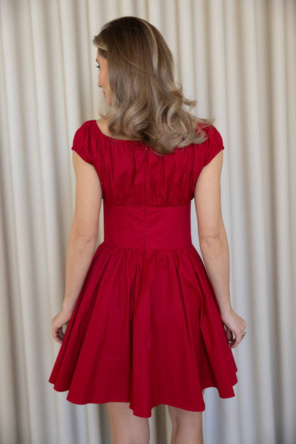 Woman wearing a red dress against a plain background