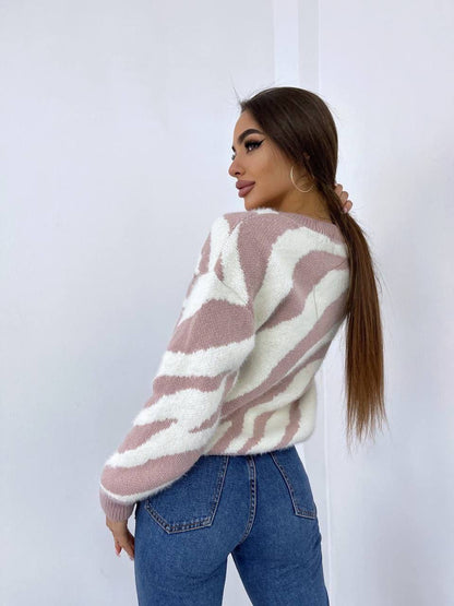 Woman wearing a patterned sweater and jeans against a white background