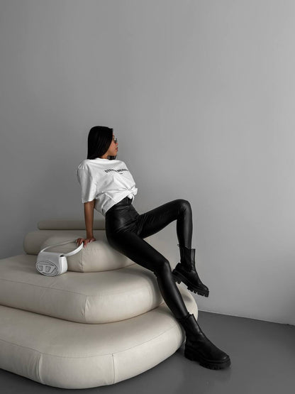 Person sitting on a modern white chair against a gray wall