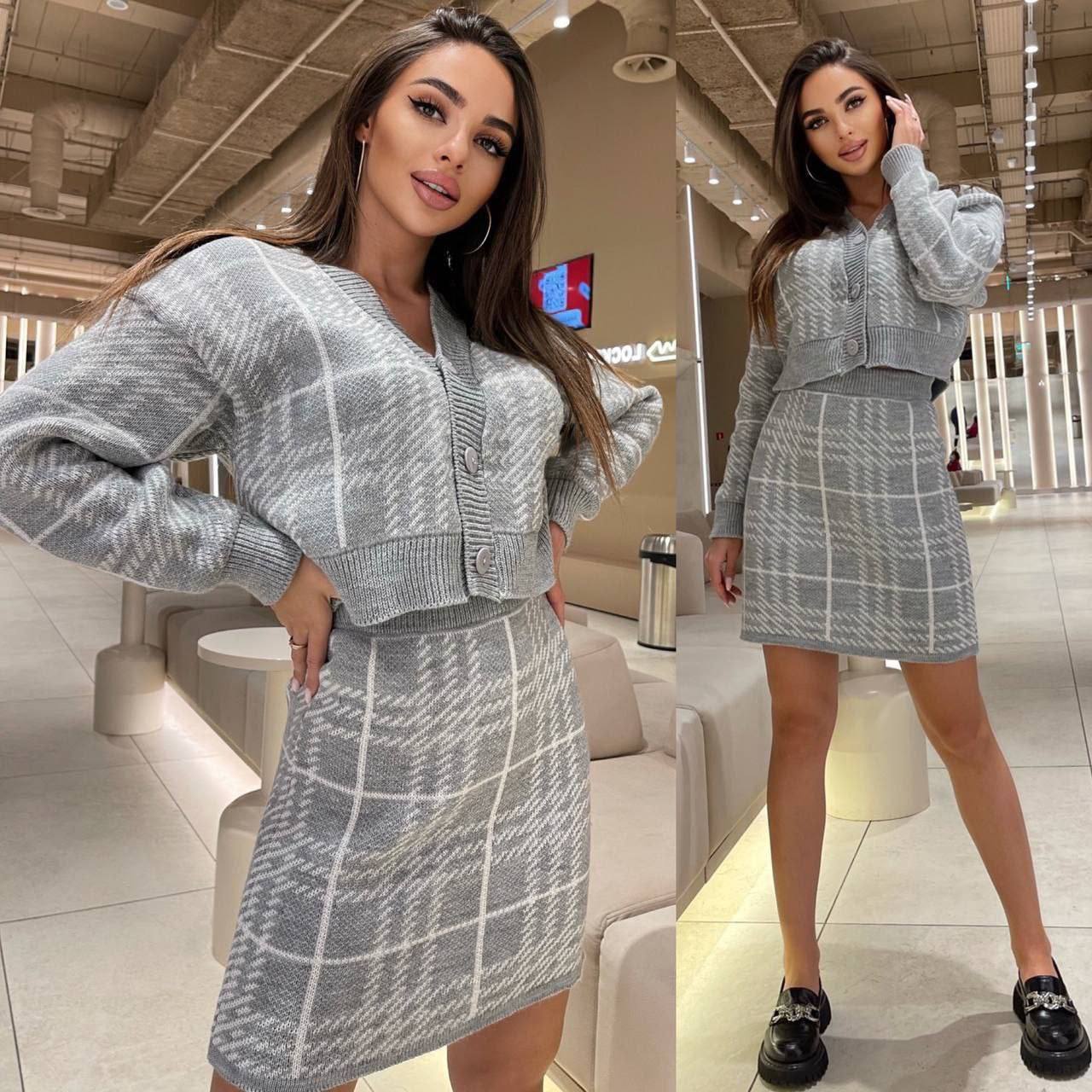 Woman wearing a gray checkered outfit in a modern indoor setting