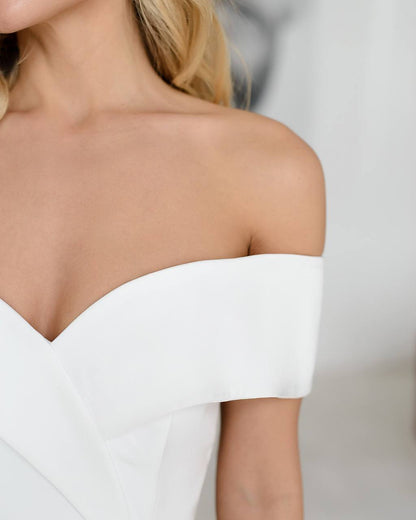 White off-shoulder top worn by a person on a plain background