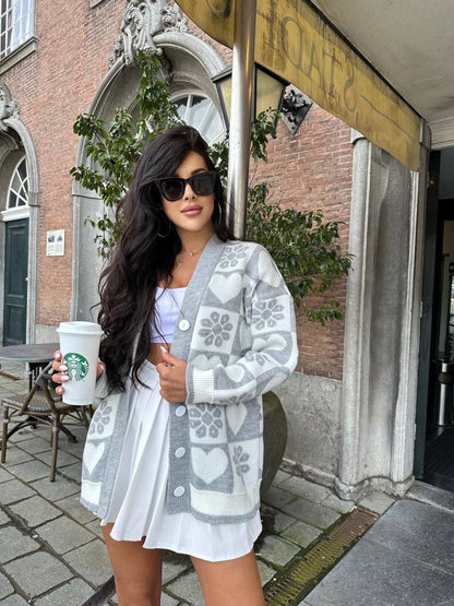 Woman holding a Starbucks cup outdoors, wearing a patterned cardigan and sunglasses.