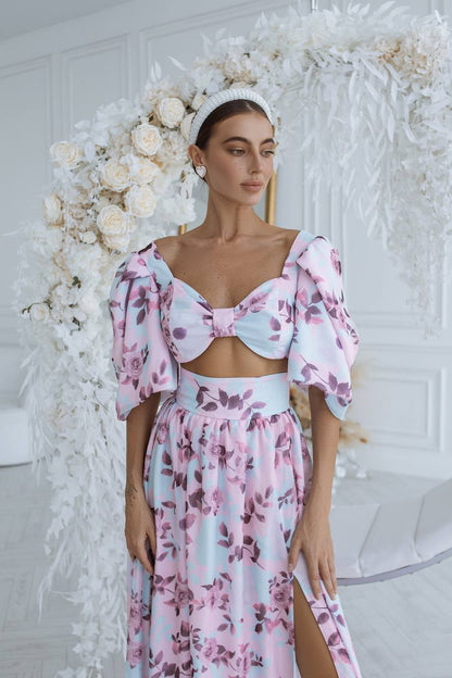 Woman in a floral dress standing in front of a decorative white flower arrangement.