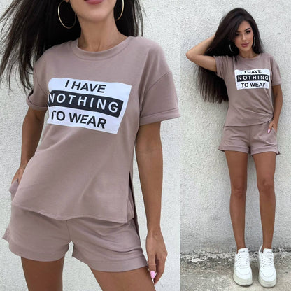 Woman wearing a brown t-shirt and shorts set with 'I Have Nothing To Wear' text, standing against a light gray wall.