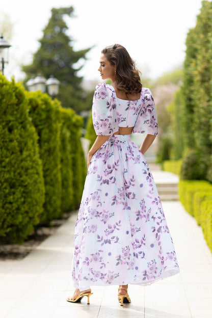 Woman in a floral dress walking on a path with greenery