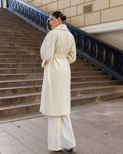 Woman in a white coat standing on steps outdoors