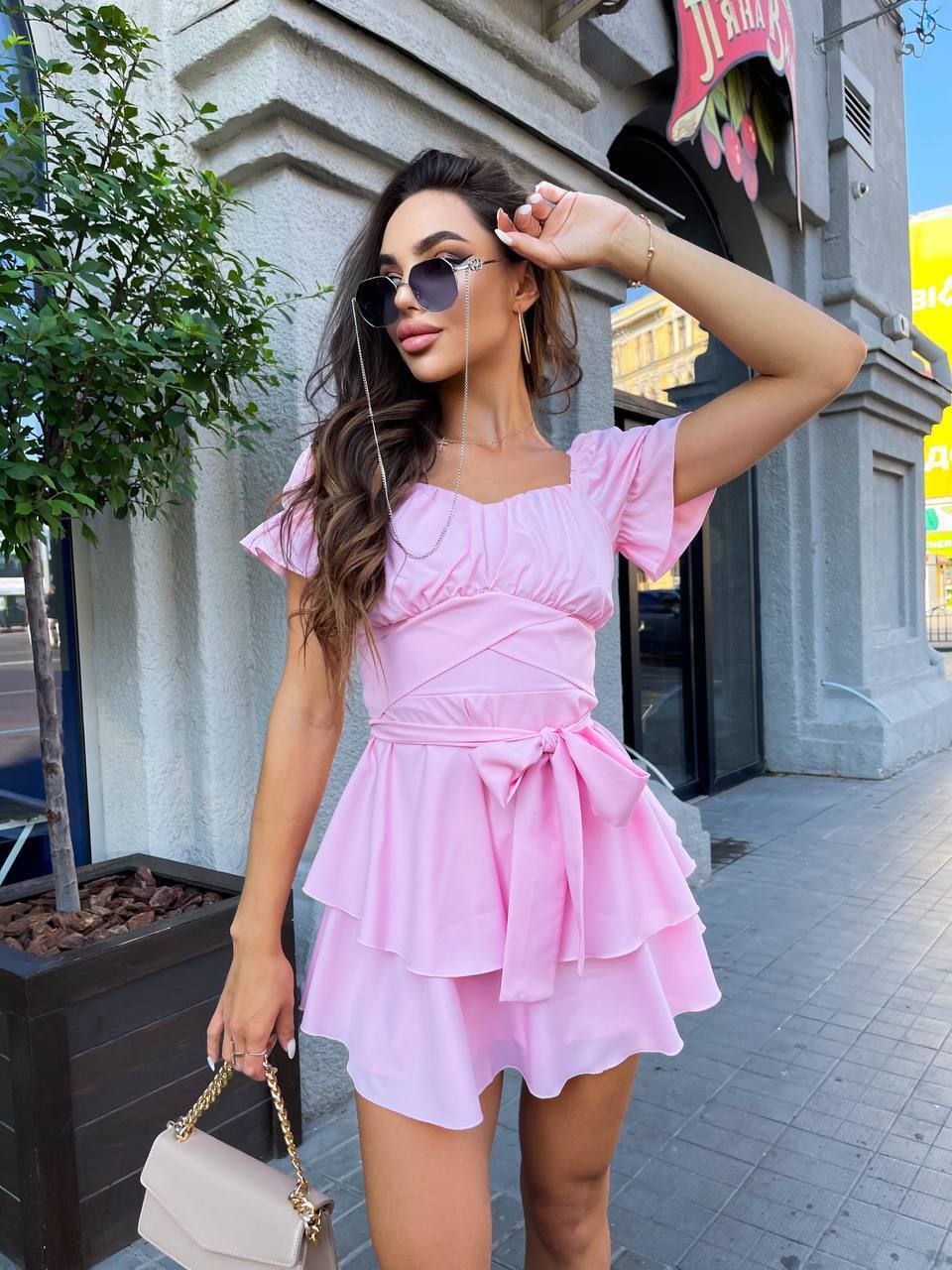 Woman in a pink dress posing on a city street.