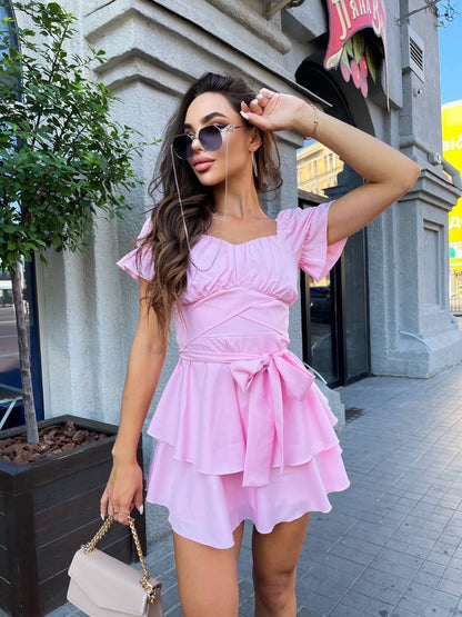 Woman in a pink dress posing on a city street.