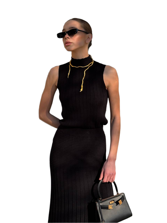 Woman in a black dress holding a handbag against a white background