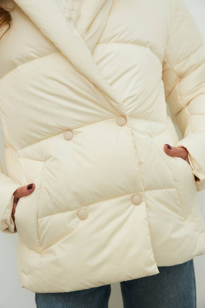 Cream-colored puffer jacket worn by a person on a white background