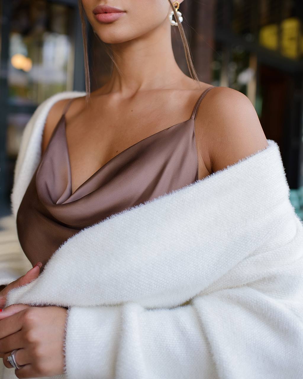 Woman wearing a brown top and white fur coat with a blurred background