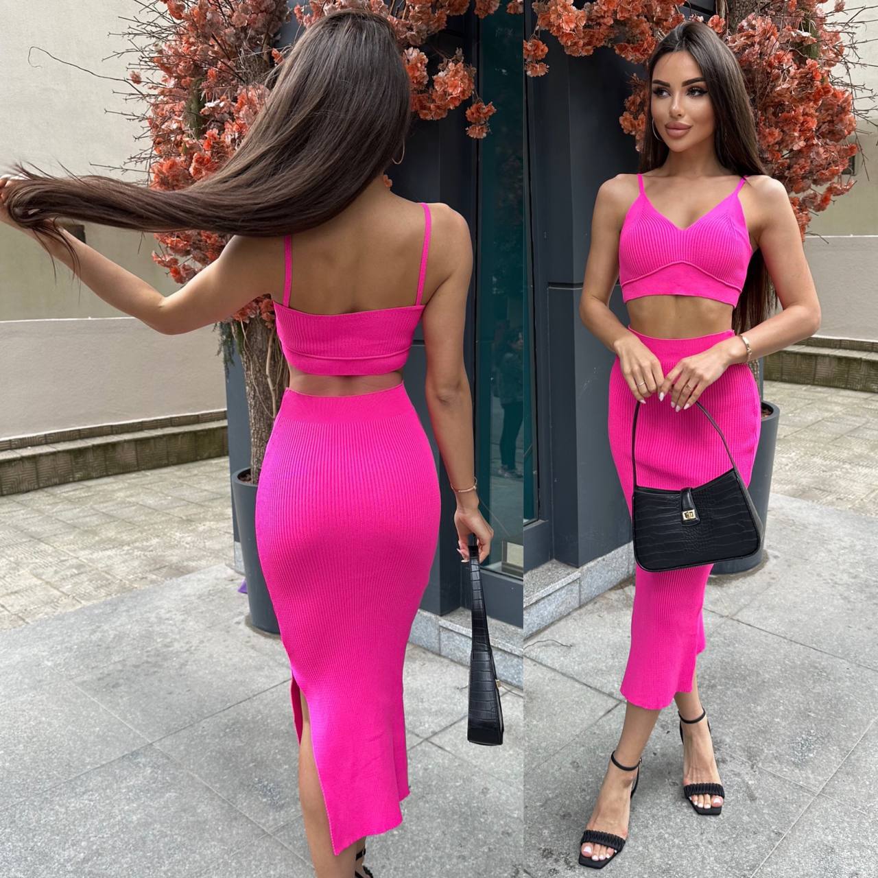 Woman in a bright pink outfit standing outdoors with a black handbag.